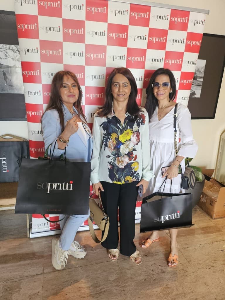 Three guests with Sopritti bags at the branded step-and-repeat at a past edition