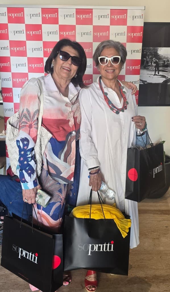 Two guests with Sopritti shopping bags at the checkered Sopritti backdrop